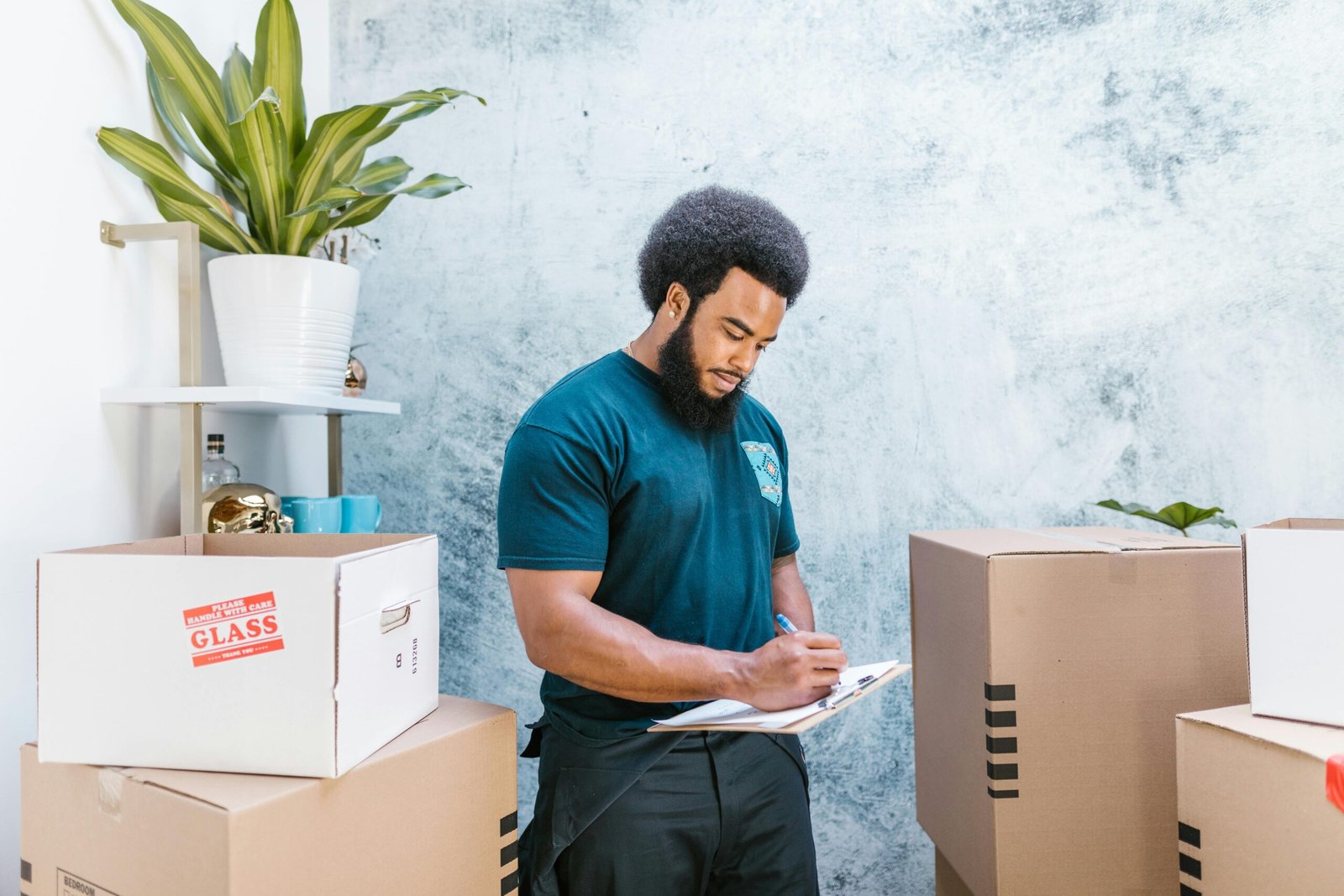 service-1 A mover with a clipboard checking packages and boxes for relocation indoors.