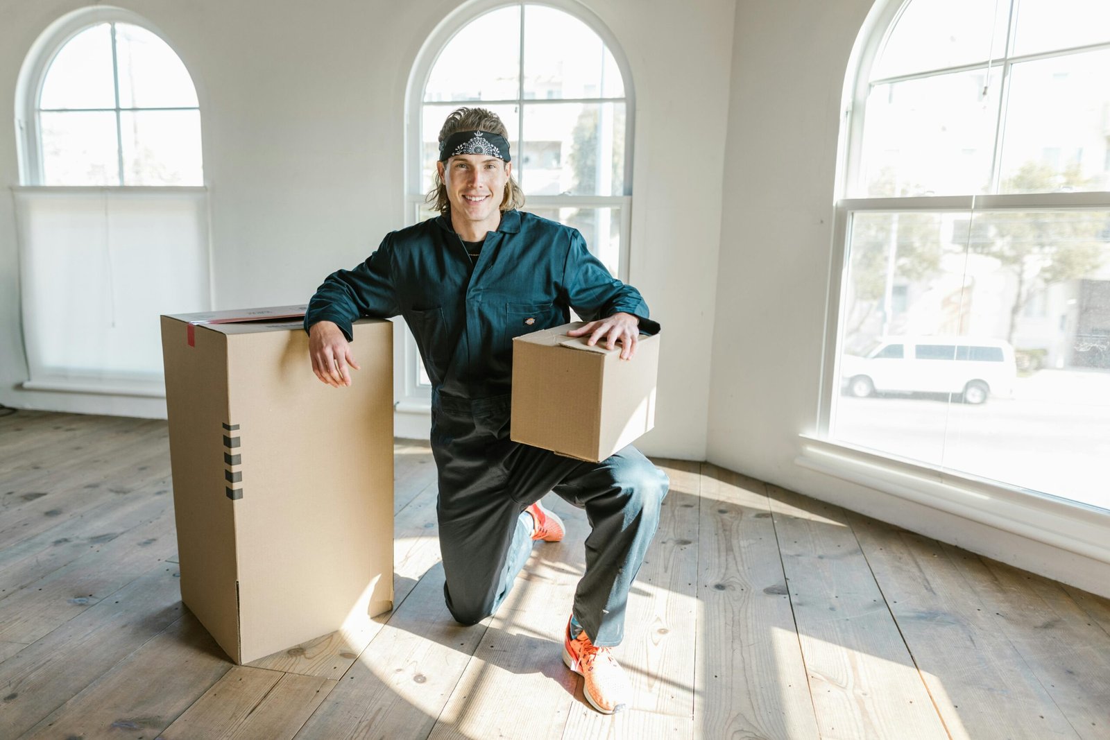 service-1 A mover in a coverall preparing boxes for relocation in a sunlit apartment.