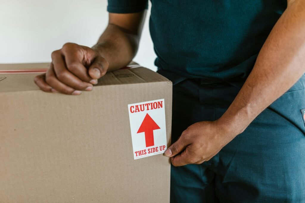 service-1 A person handling a moving box with a 'caution this side up' label indoors.